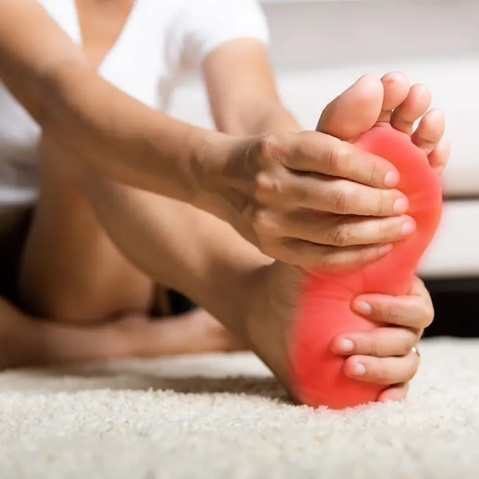Woman holding her foot in pain due to peripheral neuropathy symptoms.