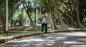 A young woman jogging outdoors, representing physical activity as a beneficial exercise for managing peripheral neuropathy symptoms and promoting nerve health.