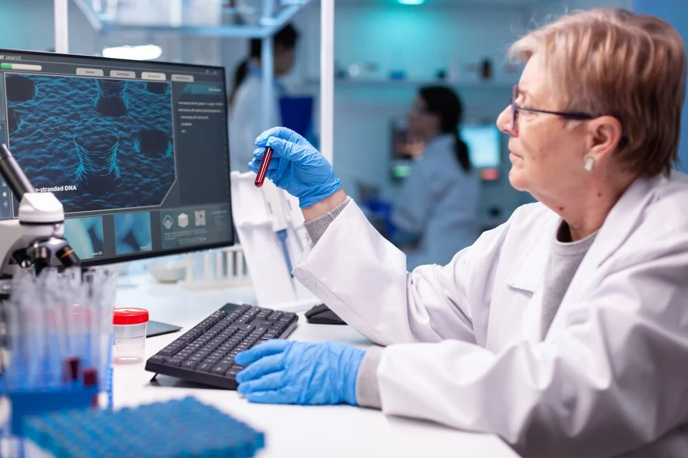 Doctor holding a blood sample in front of a diagnostic machine displaying test results