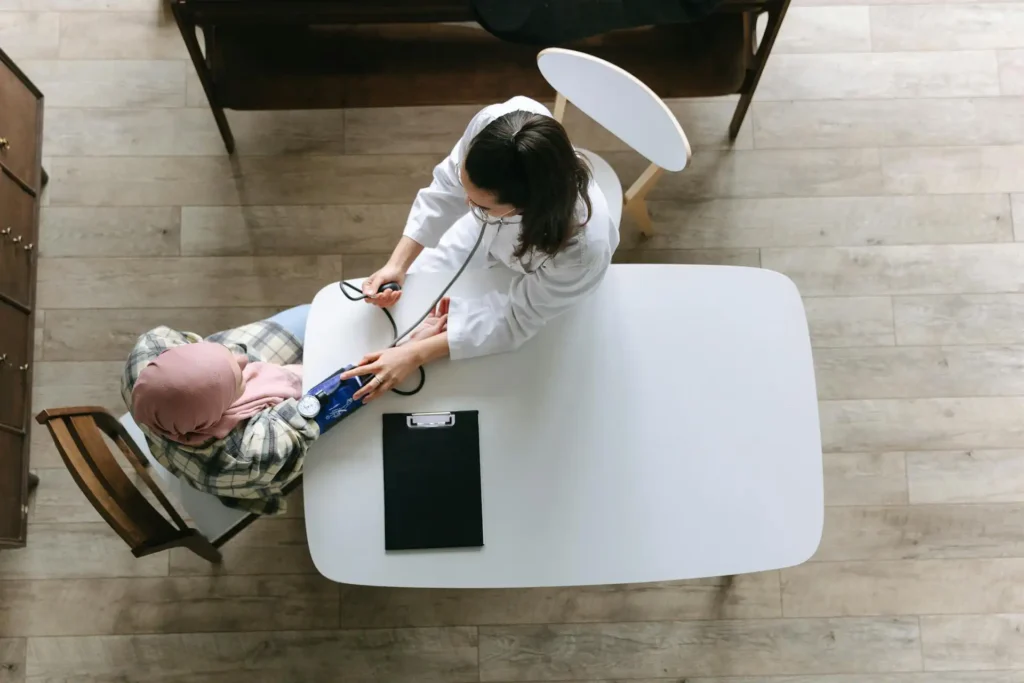 A doctor measuring a patient’s blood pressure during a clinical visit while suggesting further consultation, demonstrating attentive care and proactive health guidance.