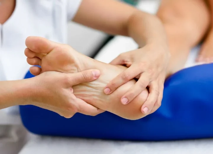 Therapist applying pressure to the bottom of a patient's foot.