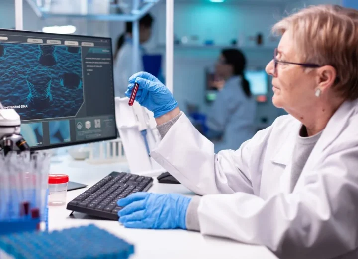 Doctor holding a blood sample in front of a diagnostic machine displaying test results